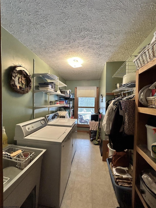 laundry room featuring sink, light tile patterned floors, a textured ceiling, and washer and clothes dryer