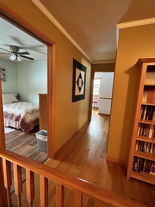 hallway with crown molding, wood-type flooring, and a textured ceiling