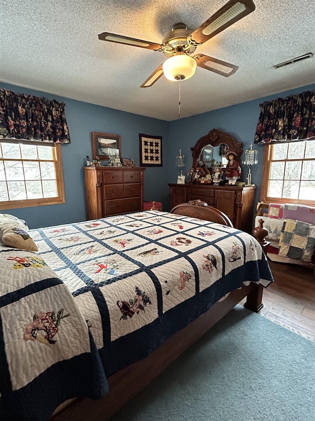 bedroom featuring hardwood / wood-style flooring, ceiling fan, and a textured ceiling