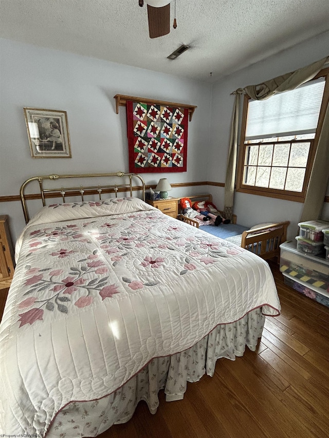 bedroom featuring ceiling fan, hardwood / wood-style floors, and a textured ceiling