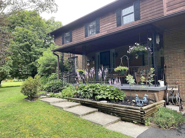 doorway to property with covered porch and a lawn