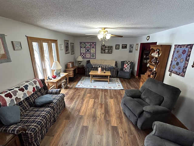 living room featuring dark hardwood / wood-style flooring, ceiling fan, and a textured ceiling