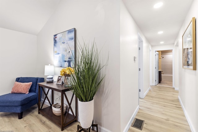 hall with lofted ceiling and light hardwood / wood-style floors