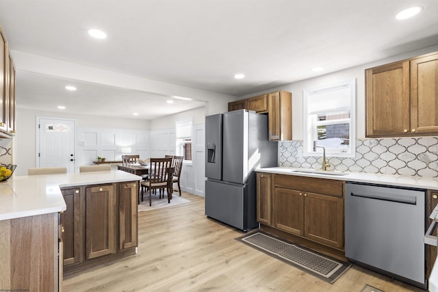 kitchen featuring sink, decorative backsplash, light hardwood / wood-style flooring, and stainless steel appliances