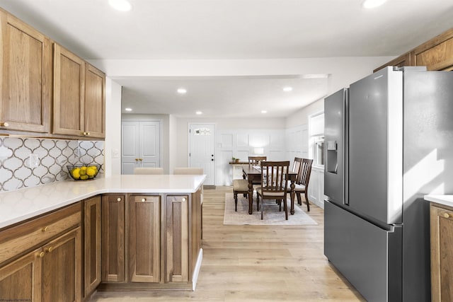 kitchen featuring light hardwood / wood-style floors, kitchen peninsula, stainless steel fridge with ice dispenser, and decorative backsplash