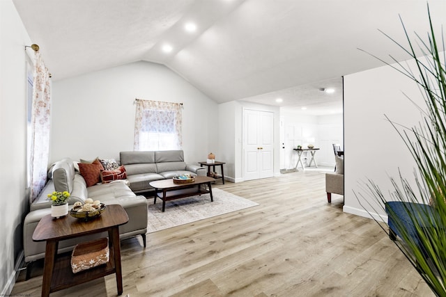 living room featuring lofted ceiling and light hardwood / wood-style flooring