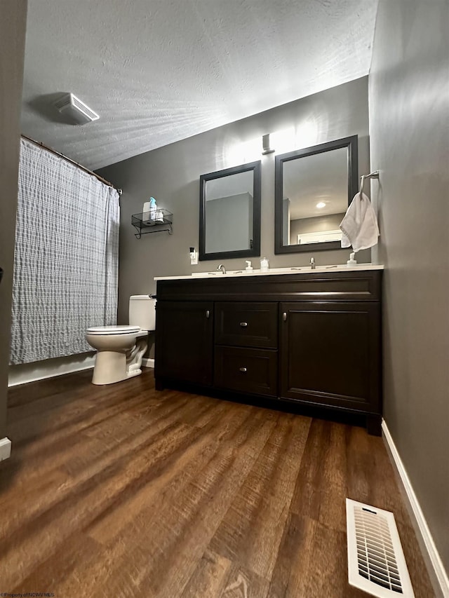 bathroom featuring hardwood / wood-style flooring, vanity, toilet, and a textured ceiling