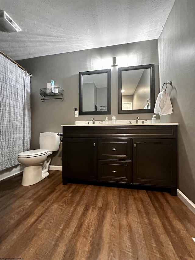 bathroom featuring vanity, toilet, hardwood / wood-style floors, and a textured ceiling