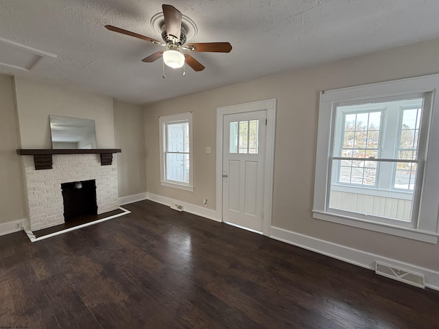 entrance foyer with plenty of natural light, a textured ceiling, a fireplace, and dark hardwood / wood-style flooring