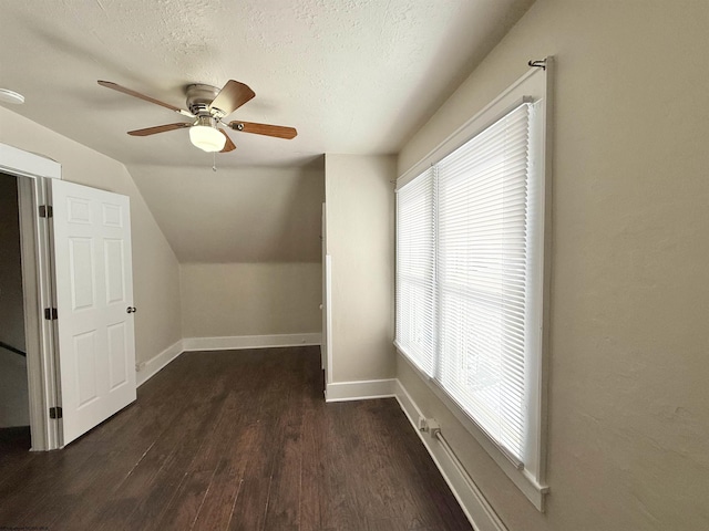 additional living space featuring dark wood-type flooring, ceiling fan, lofted ceiling, and a textured ceiling