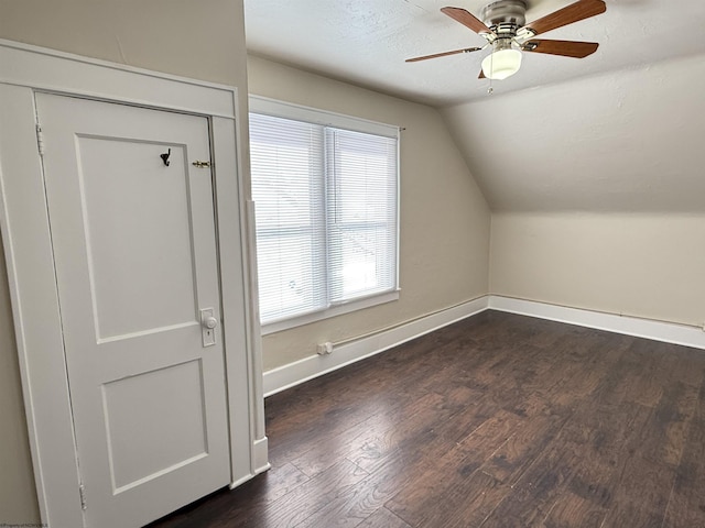 additional living space with vaulted ceiling, dark wood-type flooring, a textured ceiling, and ceiling fan