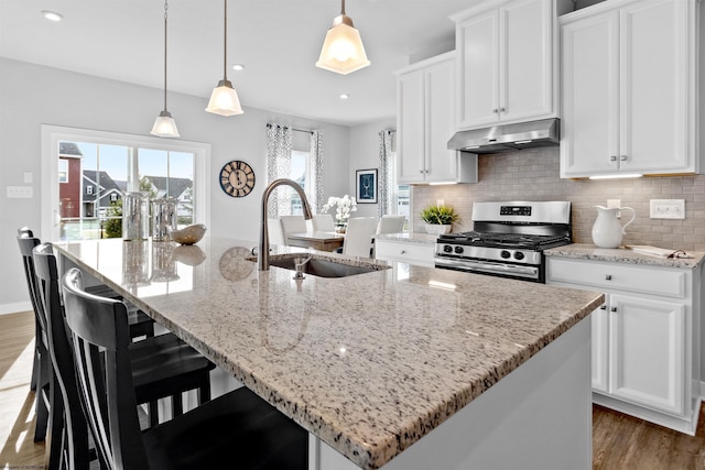 kitchen featuring sink, stainless steel range with gas cooktop, pendant lighting, a kitchen island with sink, and white cabinets