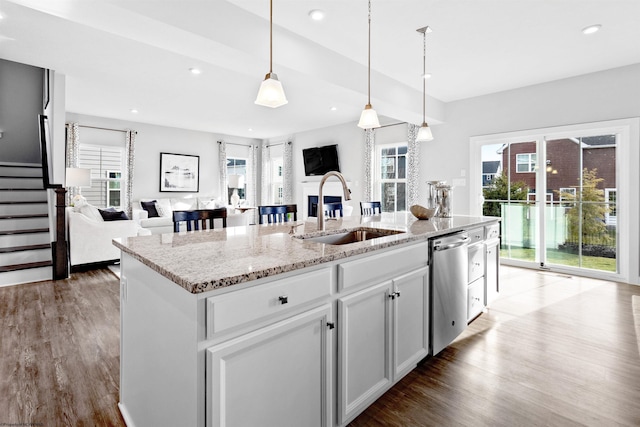 kitchen featuring white cabinets, light stone countertops, sink, and a kitchen island with sink