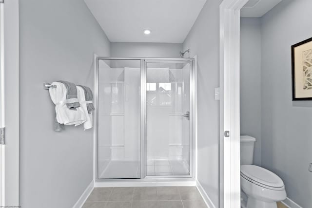 bathroom with toilet, a shower with shower door, and tile patterned flooring