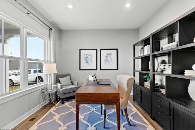 office with light wood-type flooring and a wealth of natural light