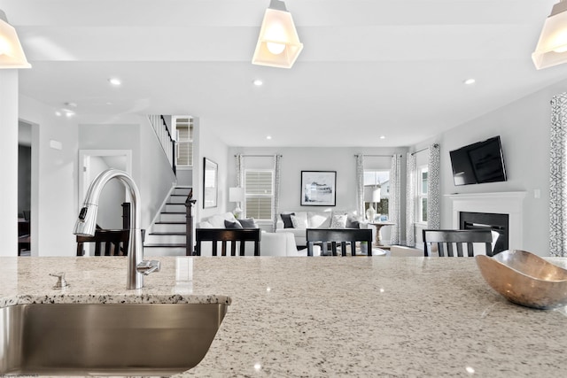 kitchen featuring light stone counters, sink, and pendant lighting