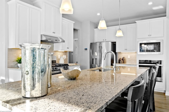 kitchen featuring pendant lighting, a kitchen island with sink, white cabinets, and appliances with stainless steel finishes