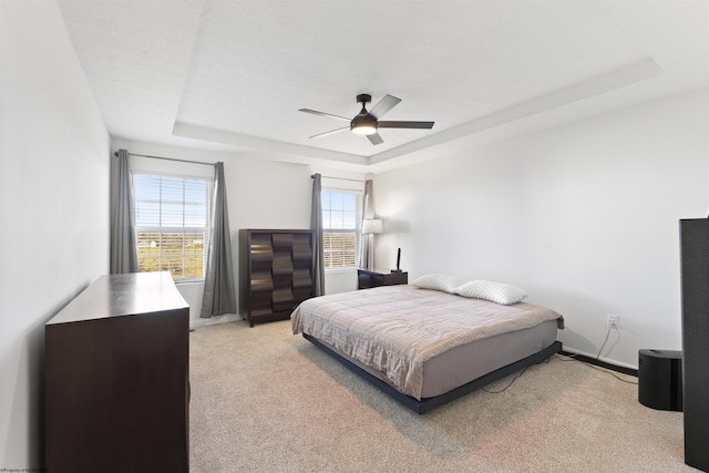 carpeted bedroom featuring ceiling fan and a tray ceiling