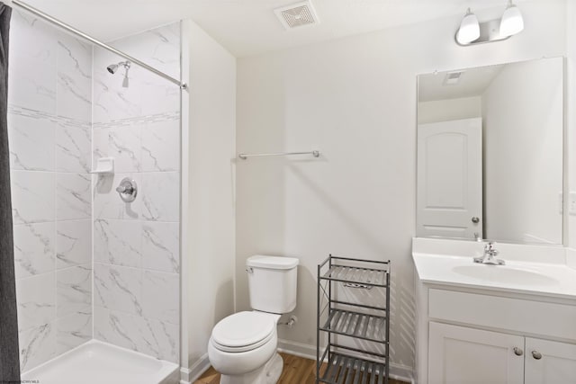 bathroom with vanity, wood-type flooring, toilet, and tiled shower