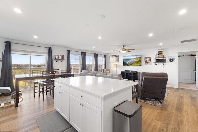 kitchen featuring a kitchen island, a barn door, white cabinets, and light hardwood / wood-style floors