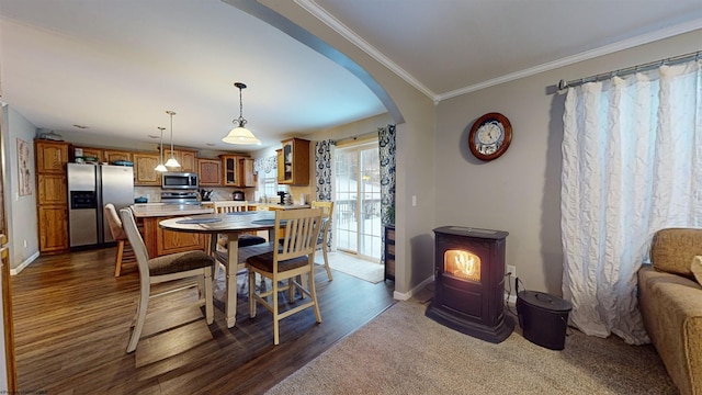 dining room with dark wood-type flooring, ornamental molding, and a wood stove