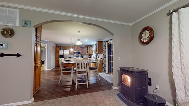 dining room with ornamental molding, a wood stove, and dark carpet