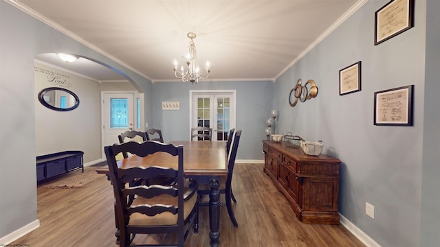 dining room with a notable chandelier, crown molding, french doors, and light wood-type flooring