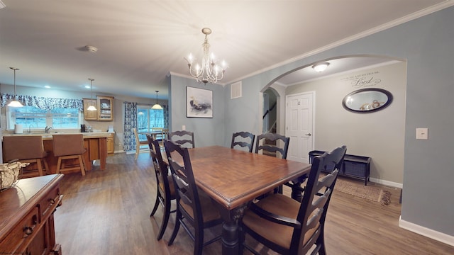 dining room featuring ornamental molding, hardwood / wood-style floors, and a notable chandelier