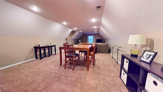 carpeted dining space with vaulted ceiling