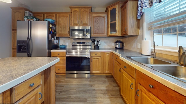 kitchen featuring tasteful backsplash, sink, light wood-type flooring, and appliances with stainless steel finishes