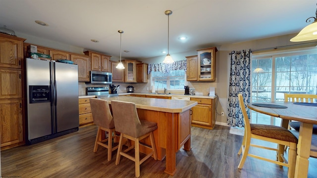 kitchen with stainless steel appliances, a center island, dark hardwood / wood-style flooring, and decorative light fixtures