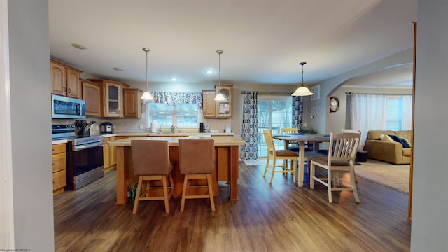 kitchen with dark wood-type flooring, sink, a breakfast bar area, a kitchen island, and stainless steel appliances