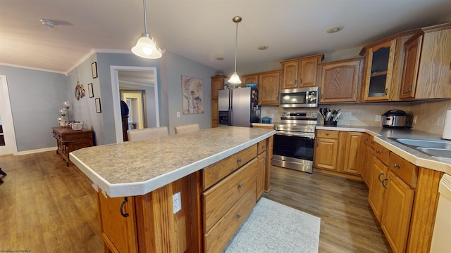 kitchen featuring pendant lighting, stainless steel appliances, a center island, tasteful backsplash, and light hardwood / wood-style floors