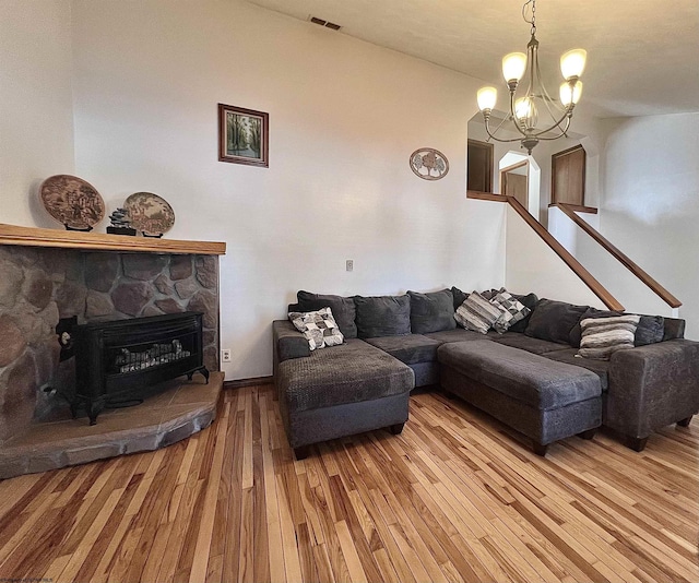 living room featuring hardwood / wood-style flooring, a fireplace, and a notable chandelier