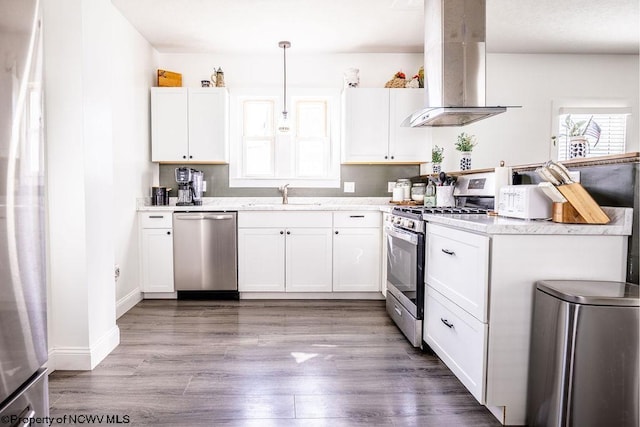 kitchen featuring sink, island range hood, decorative light fixtures, stainless steel appliances, and white cabinets