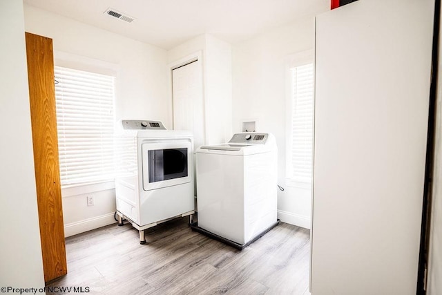 laundry room with washer and clothes dryer and light hardwood / wood-style floors