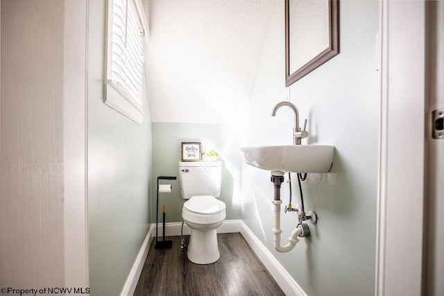 bathroom with vaulted ceiling, sink, hardwood / wood-style floors, and toilet