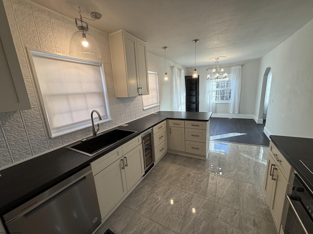 kitchen featuring sink, kitchen peninsula, pendant lighting, stainless steel appliances, and beverage cooler