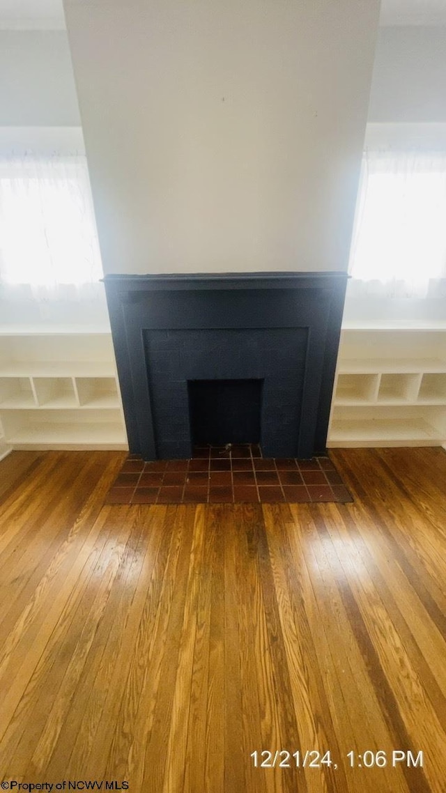 details with a tiled fireplace and hardwood / wood-style flooring