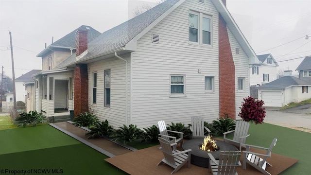 rear view of property featuring a garage and a fire pit