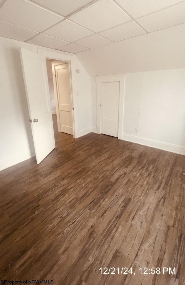 empty room with vaulted ceiling, a paneled ceiling, and dark hardwood / wood-style flooring