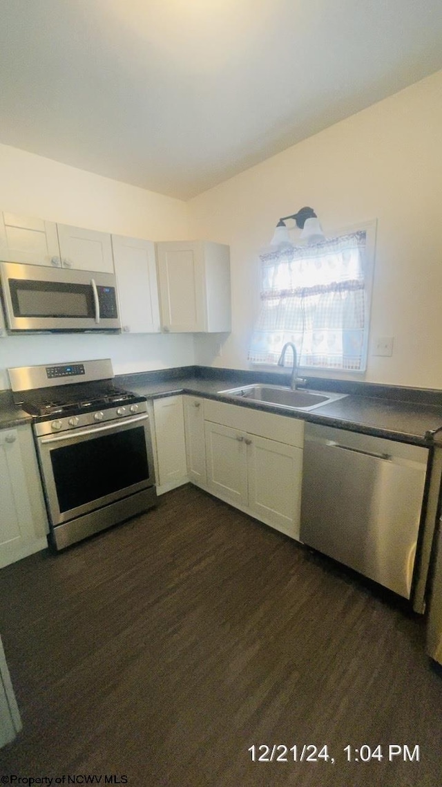 kitchen with dark hardwood / wood-style flooring, sink, stainless steel appliances, and white cabinets