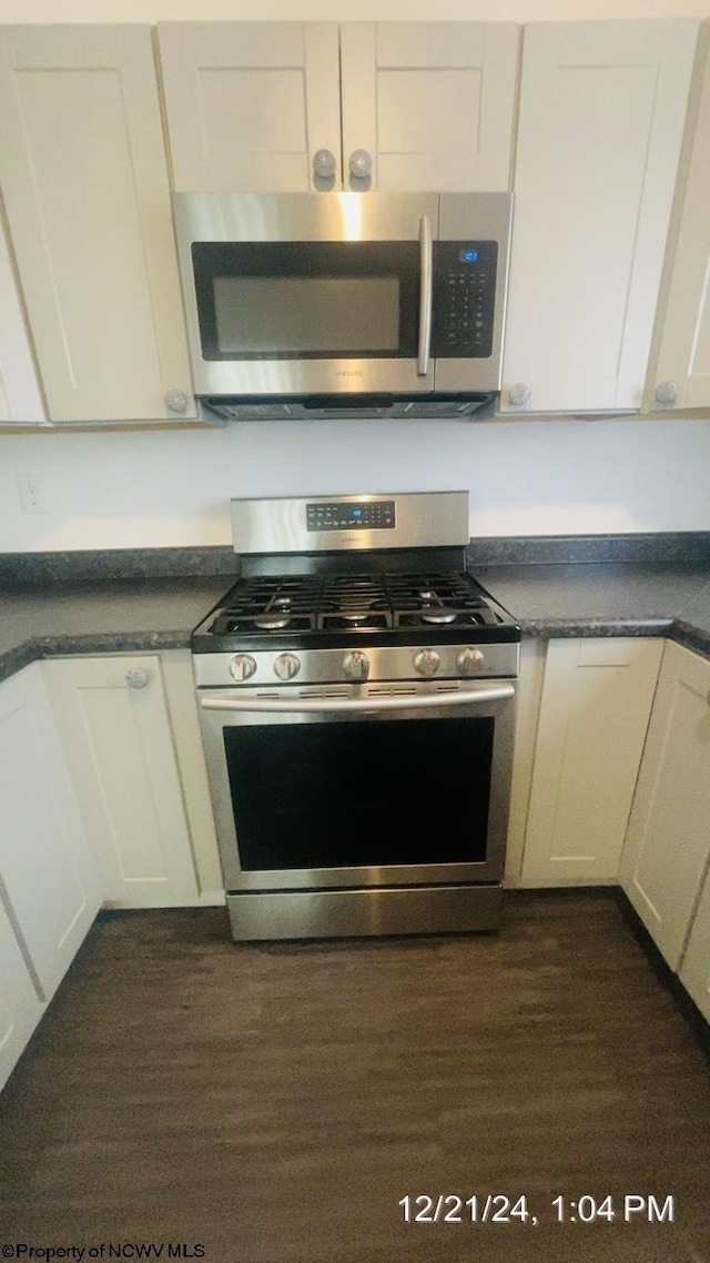 kitchen featuring appliances with stainless steel finishes, dark hardwood / wood-style floors, and white cabinets