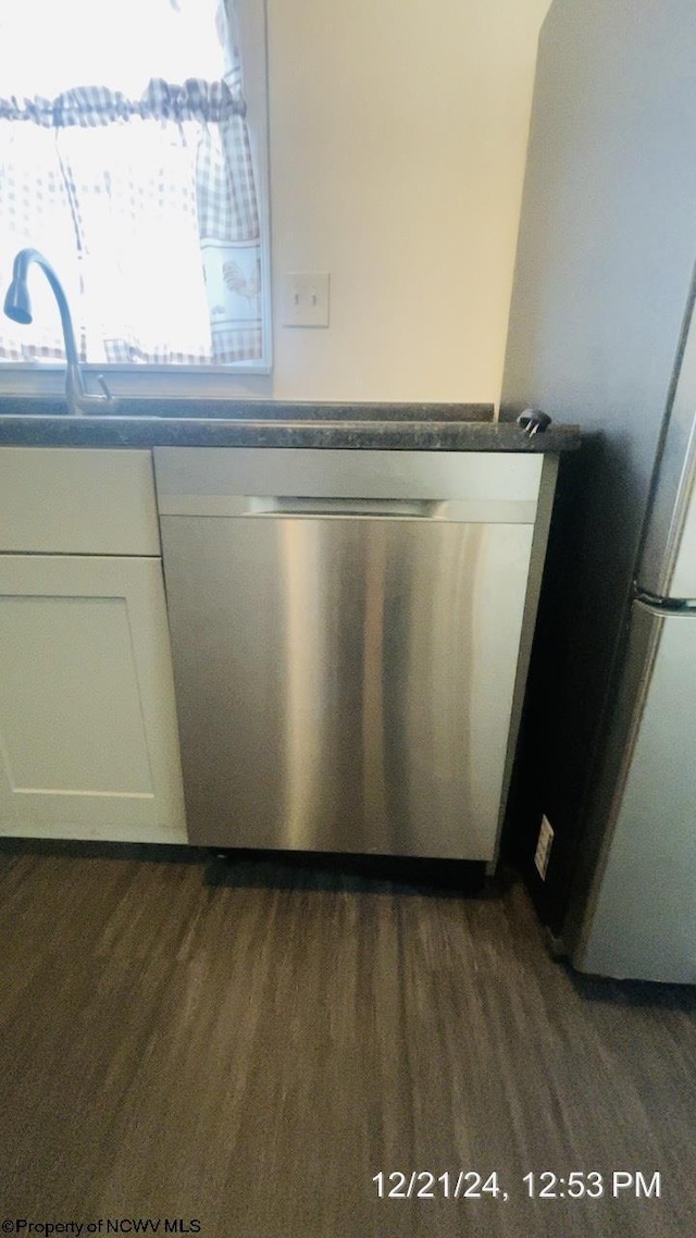 room details with appliances with stainless steel finishes, dark hardwood / wood-style floors, and white cabinets