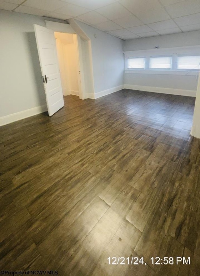 spare room with dark hardwood / wood-style floors and a drop ceiling