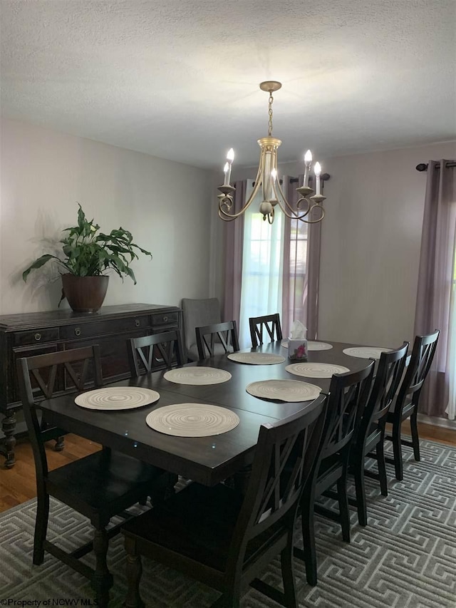 dining space featuring an inviting chandelier, dark hardwood / wood-style floors, and a textured ceiling