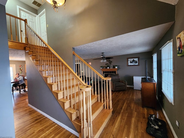 staircase with hardwood / wood-style flooring, a high ceiling, and ceiling fan