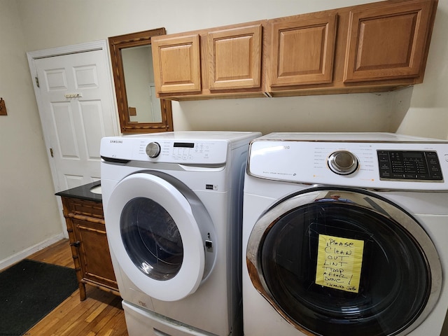 clothes washing area with cabinets, washing machine and dryer, and light wood-type flooring