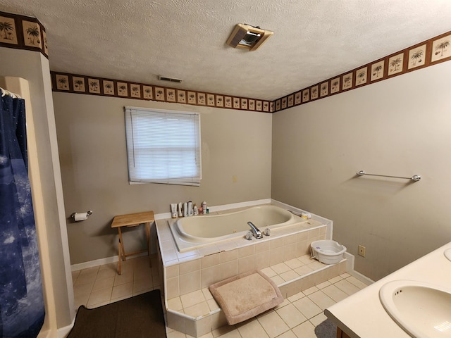 bathroom featuring tile patterned flooring, vanity, tiled bath, and a textured ceiling