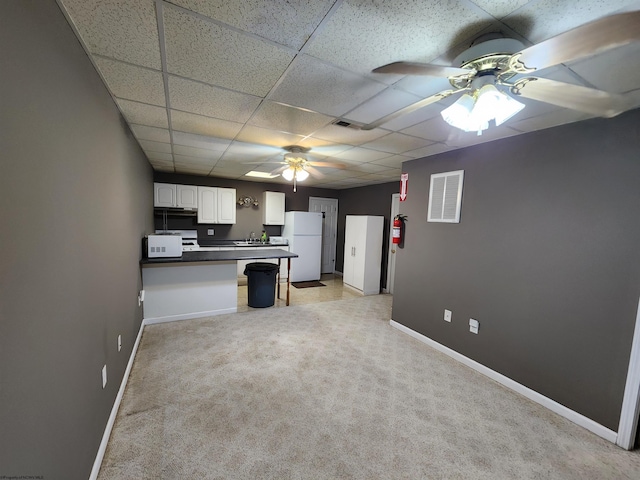 kitchen featuring a paneled ceiling, white cabinetry, white fridge, light colored carpet, and kitchen peninsula